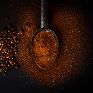 gemahlener Kaffee in Löffel und Kaffeebohnen